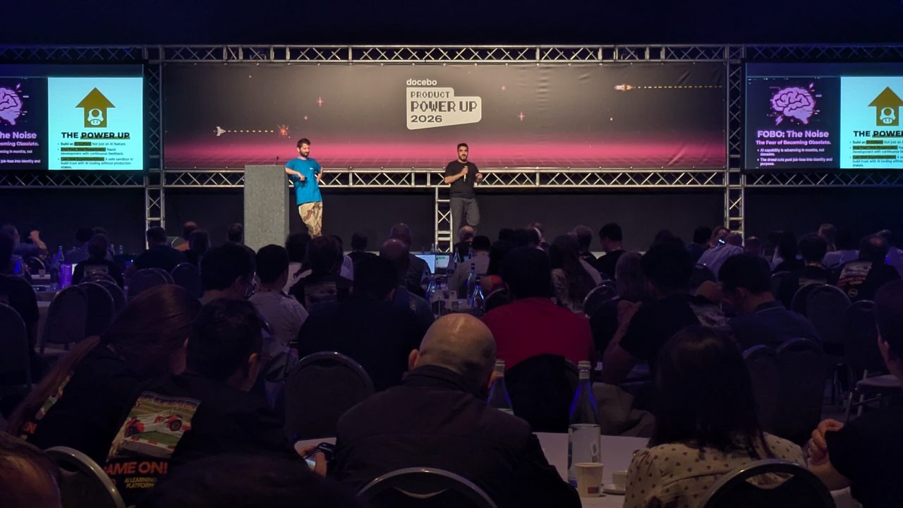 Luca Fregoso on stage with a co-host at Docebo GAME UP! Product Power Up 2026, addressing a full audience.